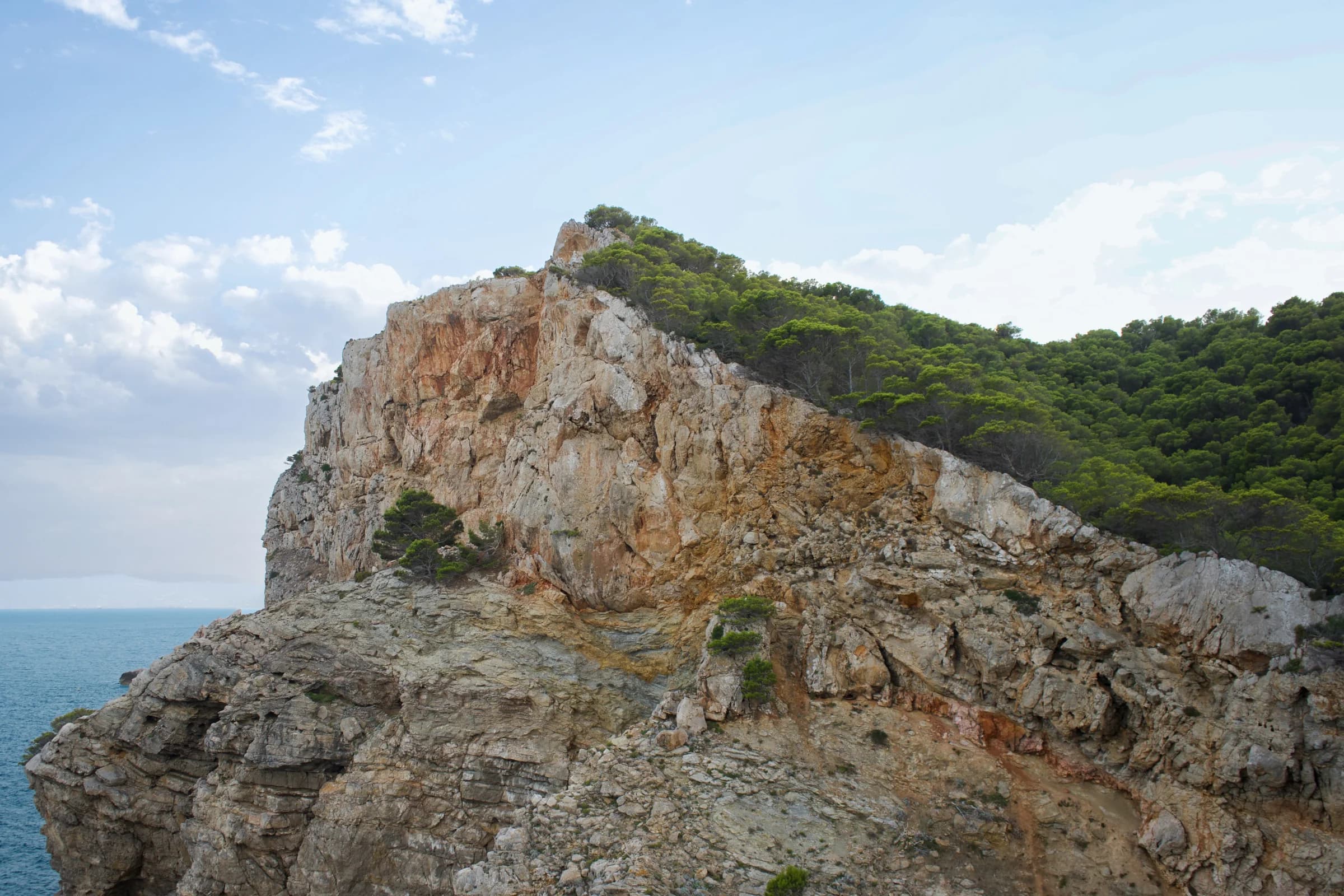 A vast orange cliff meeting the Mediterranean Sea