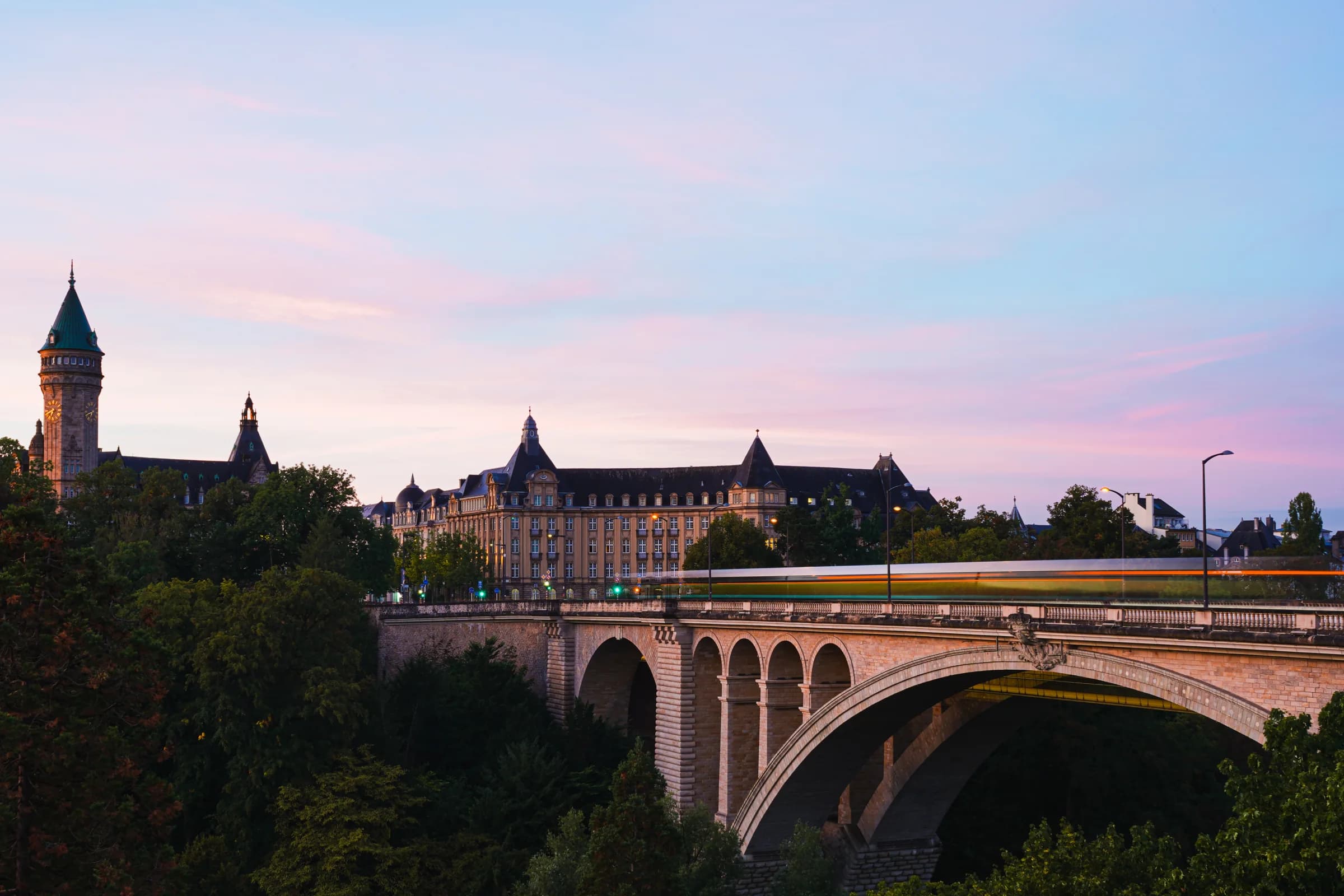 Luxembourg at dawn, with an arched bridge leading towards the city