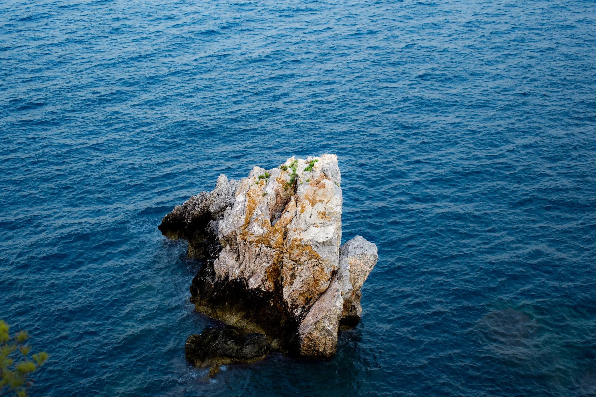 A pale rock surrounded by clear blue Mediterranean water