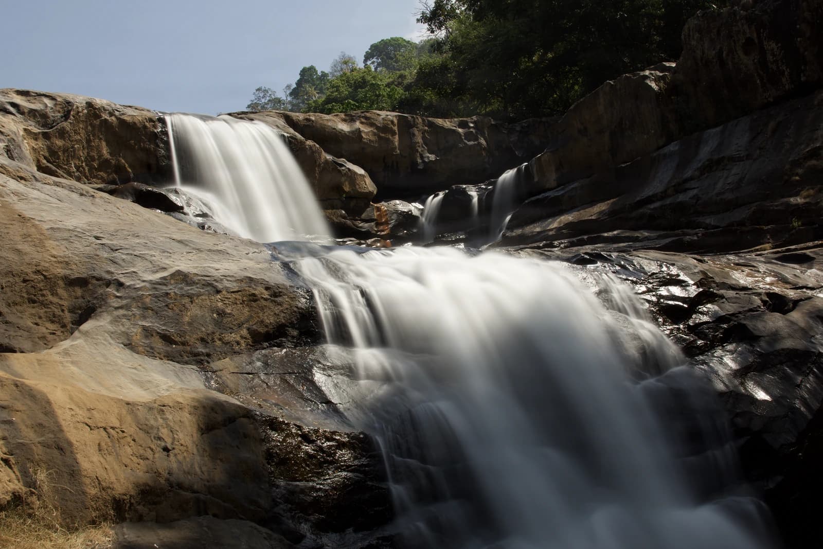 Cascading water tumbles over weathered stone in soft, misty motion.