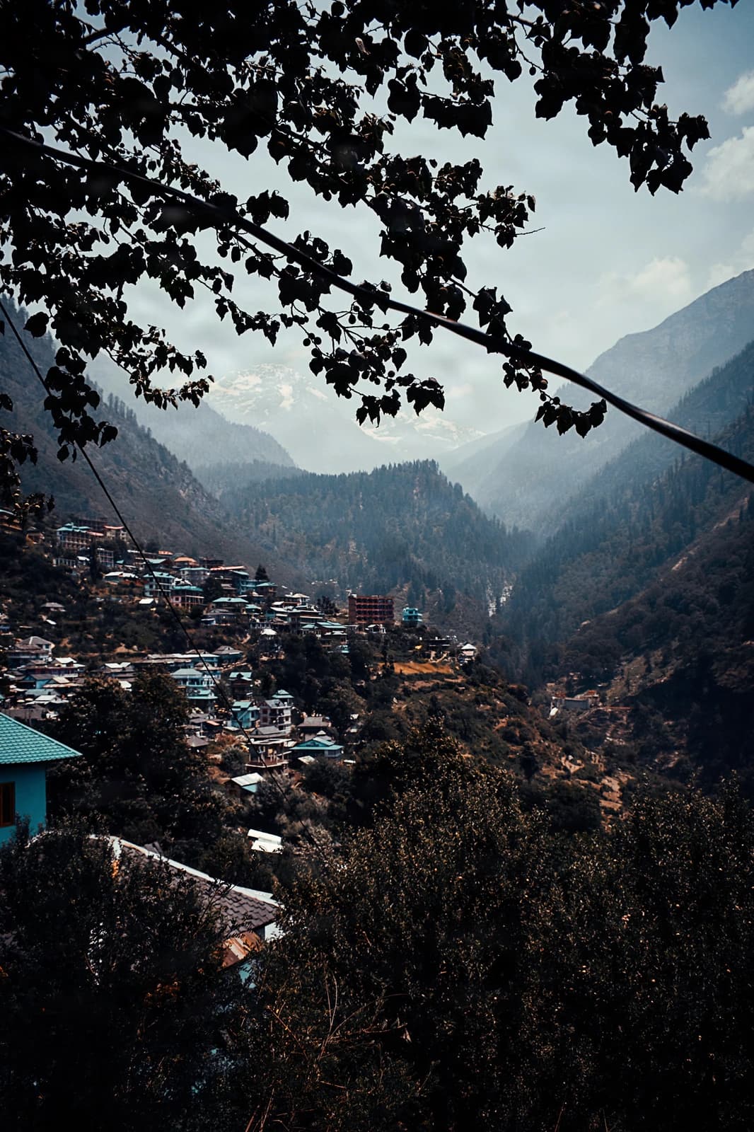 Mountain village nestled in misty valley beneath snow-capped peaks.